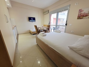 A hotel room with a bed, a TV, a desk with a chair, a window, and a balcony view.