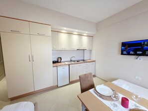 A modern kitchen with white cabinets, a built-in oven, and a dining area with a table set for two.