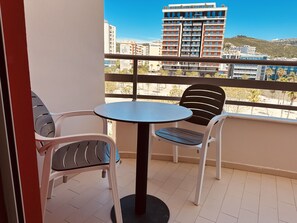 A balcony with a round table and two chairs, overlooking a cityscape with buildings and a hill. - Thoma's K Studios – Double Studio with Balcony (Vlorë)