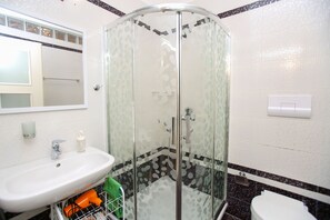 A bathroom with a glass-enclosed shower, a sink with a mirror, and a toilet.