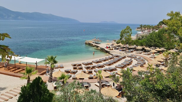 Un complexe hôtelier de bord de mer équipé de chaises longues, de parasols et offrant une vue sur la mer.