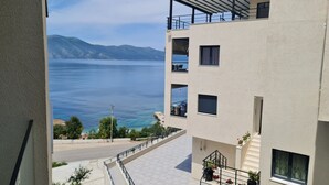 Un immeuble à plusieurs étages doté de balcons qui donnent sur un plan d’eau et sur des montagnes situées au loin.