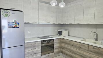 Een koelkast, een microgolfoven, een oven, kookgerei, borden en bestek