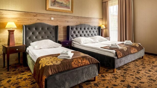 A hotel room with two beds, wooden headboards, a framed picture on the wall, and a patterned carpet. - Great Polonia Kraków Kazimierz  (Kraków)