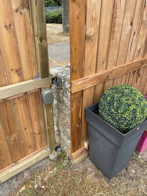 A wooden gate with a metal latch, a stone wall, and a potted plant.
