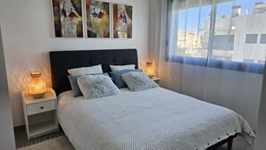 A bedroom with a bed, two bedside tables, a nightstand, a window with a view, and three wall-mounted artworks. - Modern penthouse close to Arenal beach with big top veranda. (Jávea)