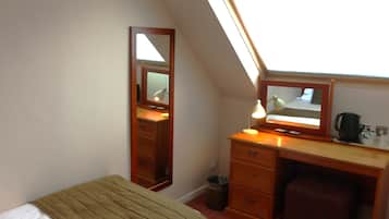 A room with a bed, a desk, a chair, a mirror, a lamp, and a window.