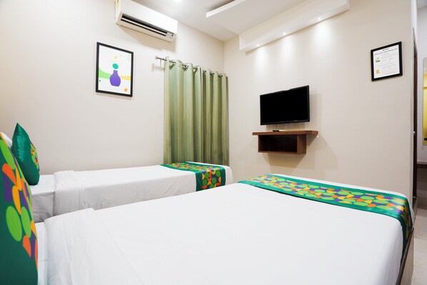 A hotel room with two single beds, a flat-screen TV mounted on the wall, and a green curtain. - Treebo Pride inn Raidurg (Hyderabad)