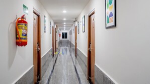 A hotel hallway with doors, a fire extinguisher, and framed artwork on the walls. - Treebo Pride inn Raidurg (Hyderabad)