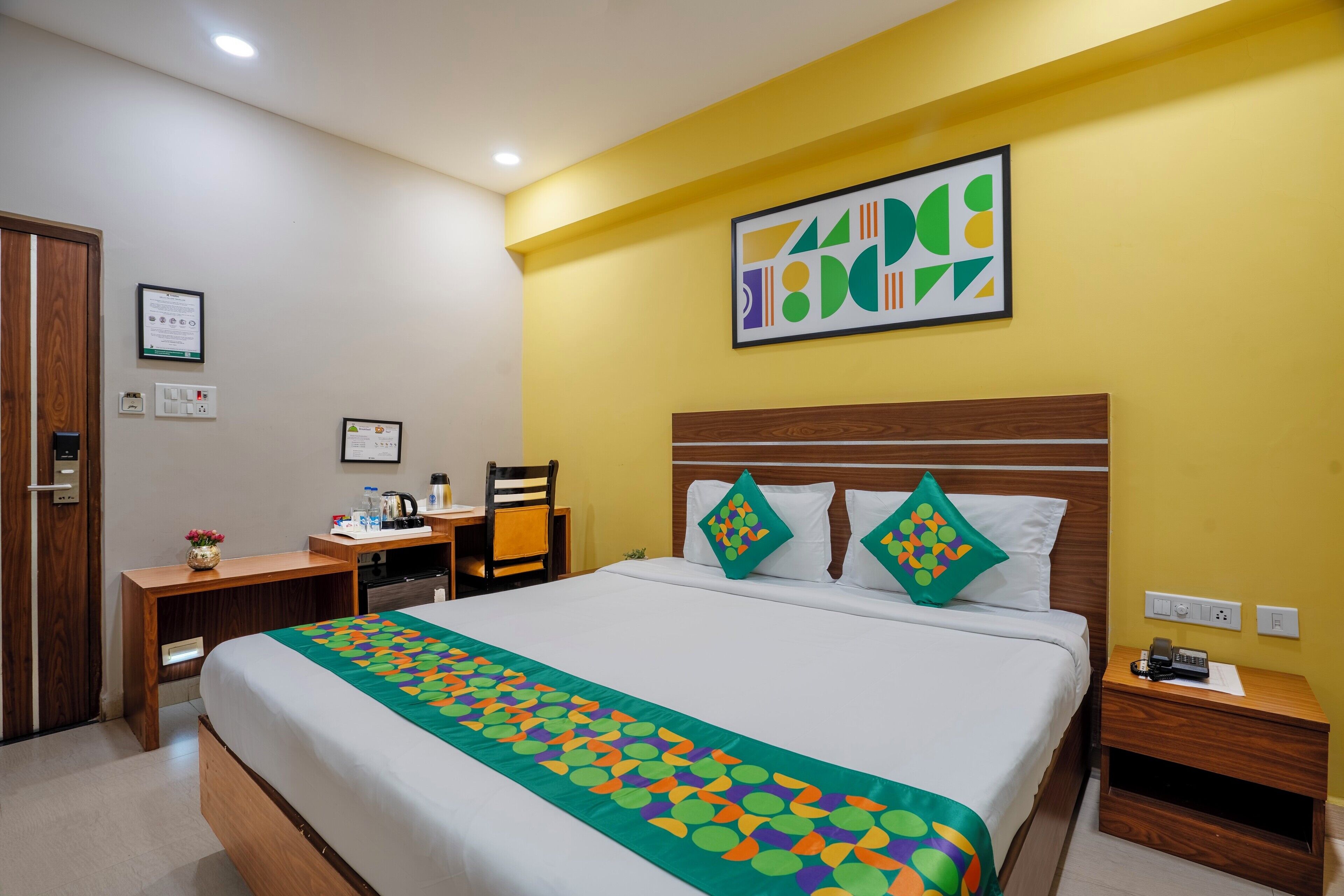 A hotel room with a large bed, a wooden headboard, two nightstands, a desk, and a chair.