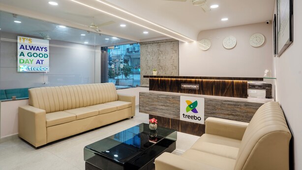 A modern reception area with a sofa, a reception desk, and a glass coffee table. - Treebo Pride inn Raidurg (Hyderabad)