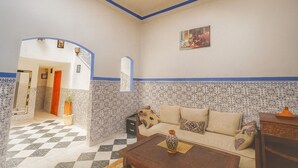 A living room with a checkered floor, a sofa, a coffee table, and a decorative vase. - Riad Amirkesh and Pool (Marrakech)