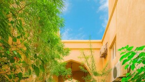 A corridor with tiled flooring, arches, and greenery. - Riad Amirkesh and Pool (Marrakech)