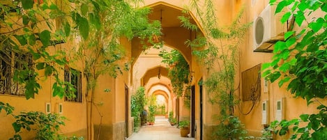 Un pasillo con suelo de baldosas, arcos y plantas.