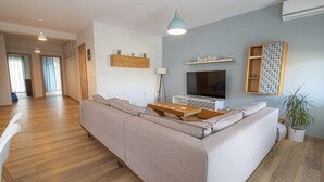 Ett modernt vardagsrum med en soffa, en tv, trähyllor och en krukväxt.