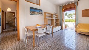 A compact living space with a dining area, a sofa, and a view through a door. - Appartamenti Costa Sud Gallipoli (Torre Suda)