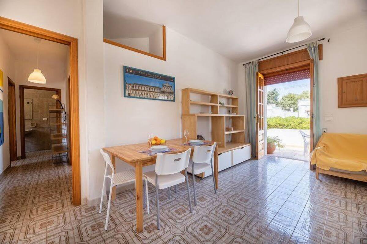 A compact living space with a dining area, a sofa, and a view through a door.
