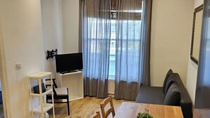 A modern living room with a wooden dining table, chairs, a TV, and a sofa. - London Charm - Moscow Road Apartment (London)