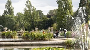 A serene garden with a fountain, water lilies, and stone urns. - London Charm - Moscow Road Apartment (London)