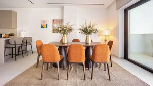 Un comedor moderno con una mesa de madera, seis sillas color naranja y dos jarrones con flores.