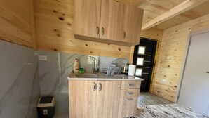Une cuisine de taille réduite, dotée de meubles en bois, d’un plan de travail en marbre et d’une petite poubelle.