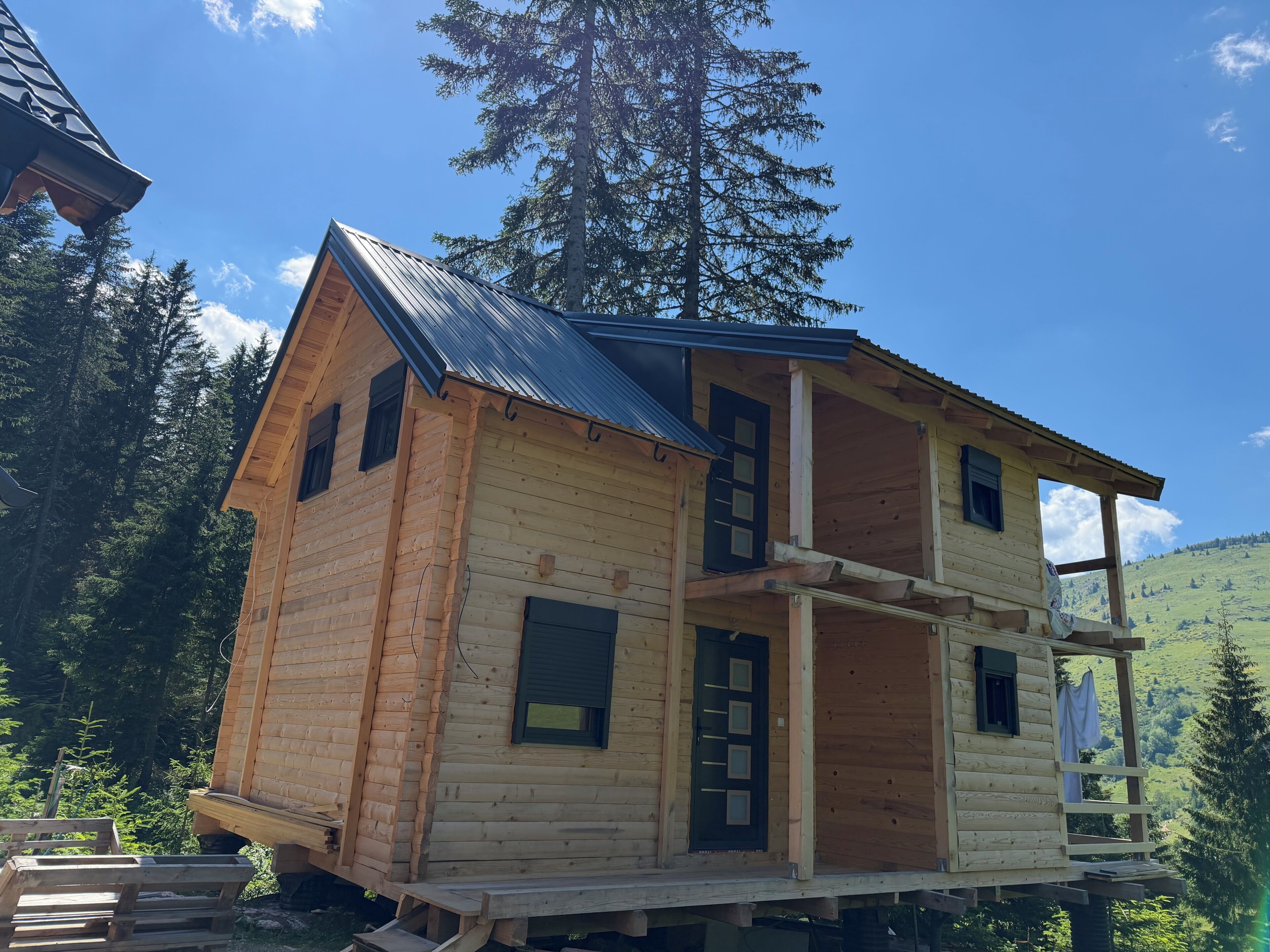 Una cabaña de madera con balcón, chimenea y ventana.