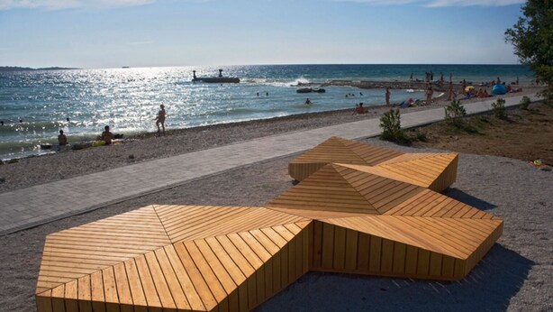 Ein Strand mit Holzbauten und freiem Blick auf das Meer.