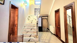 A staircase with marble steps, wooden doors, and a radiator. - Ancient Tagayev Hotel (Bukhara)