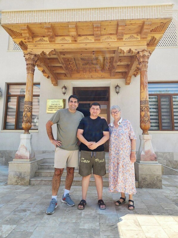 A wooden pergola with intricate carvings, a stone staircase, and a sign indicating a family guest house. - Ancient Tagayev Hotel (Bukhara)