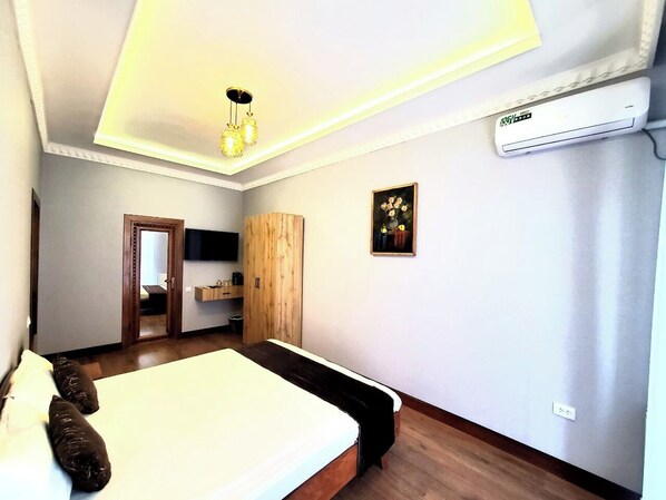 A bedroom with a bed, a wardrobe, a desk, and a painting on the wall. - Ancient Tagayev Hotel (Bukhara)
