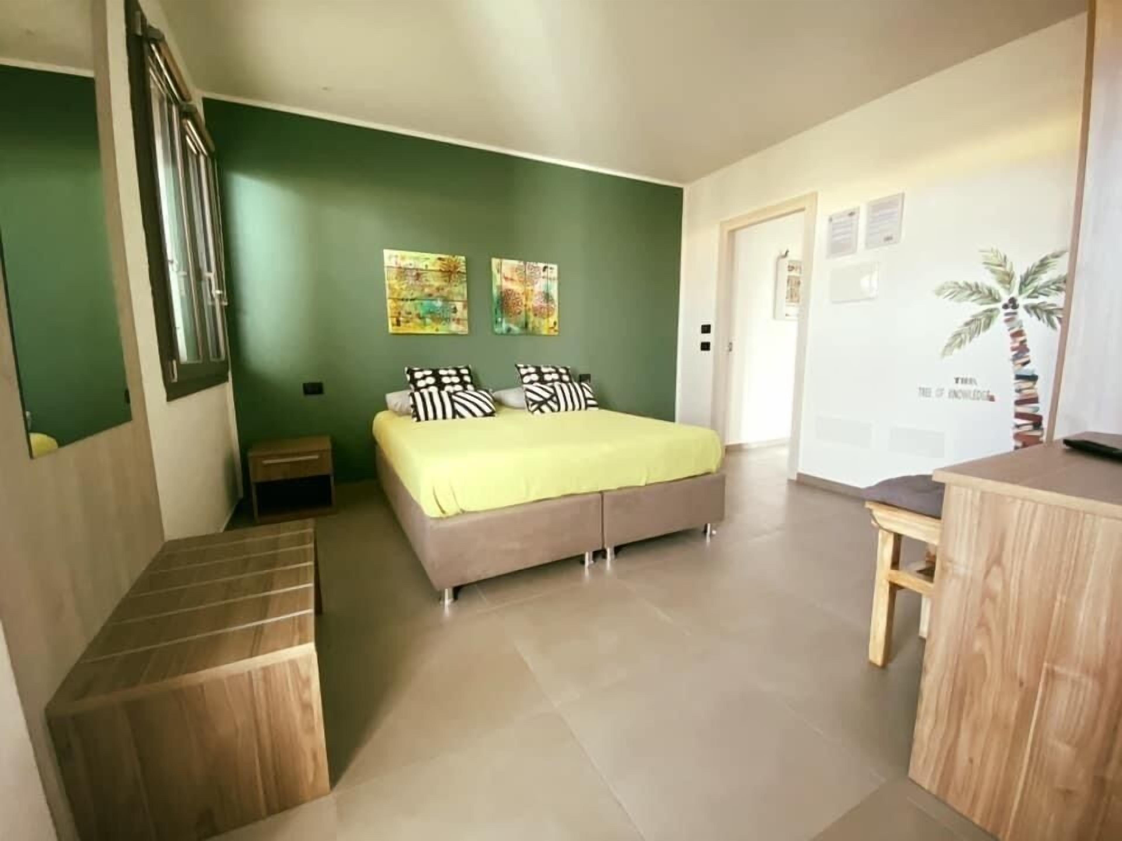 A bedroom with a bed, a nightstand, a wooden bench, and a desk.