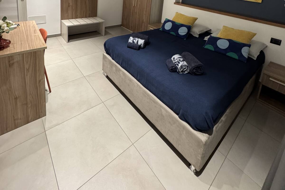 Ein modernes Schlafzimmer mit einem großen Bett, einem Holztisch, einem Kleiderschrank und einem Spiegel.