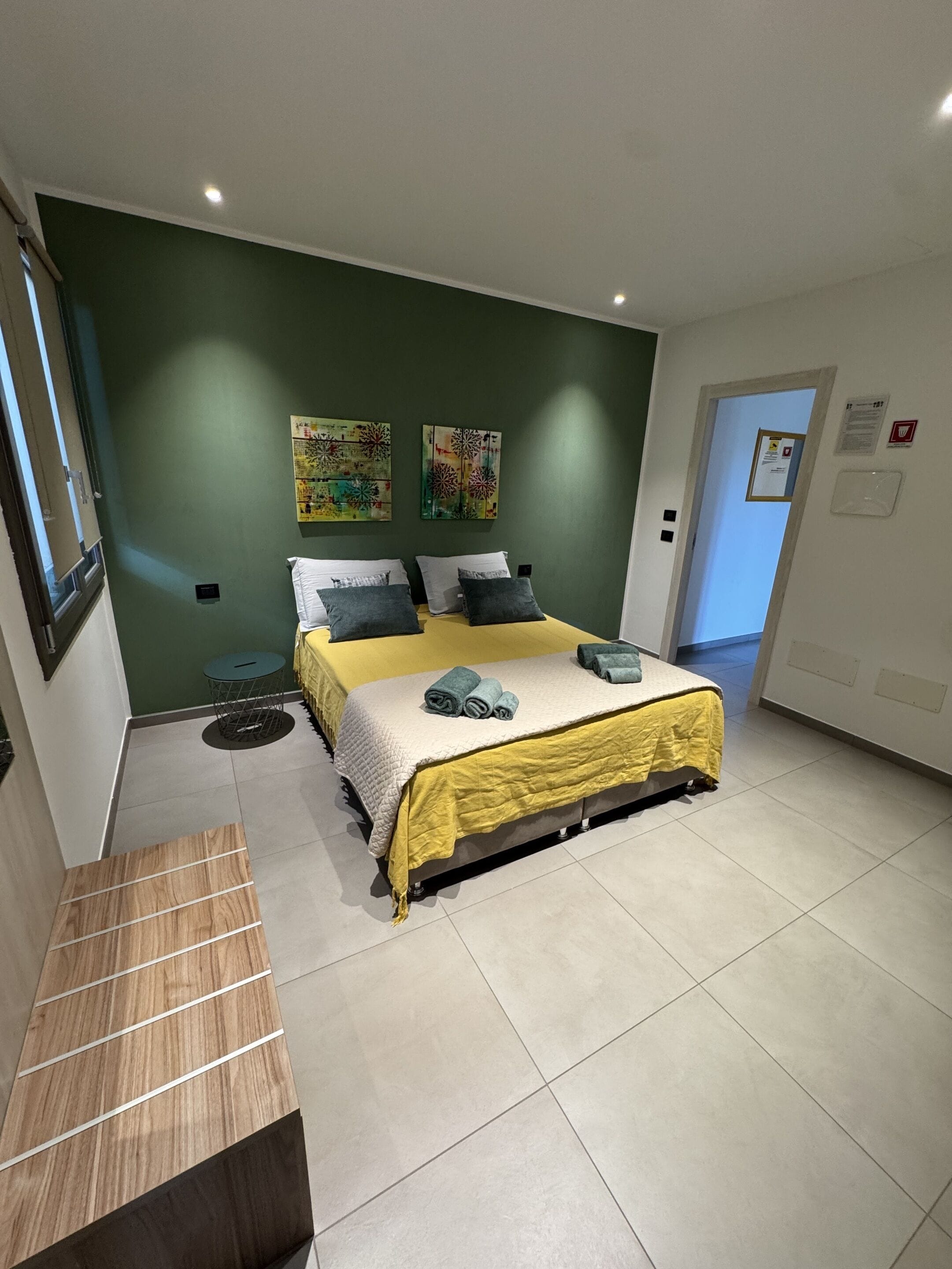 Un dormitorio con cama, paredes verdes y obras de arte.