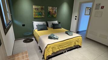 Un dormitorio con cama, paredes verdes y obras de arte.