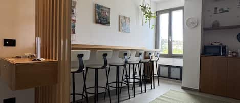 A modern kitchen with a wooden island, bar stools, and a green rug.