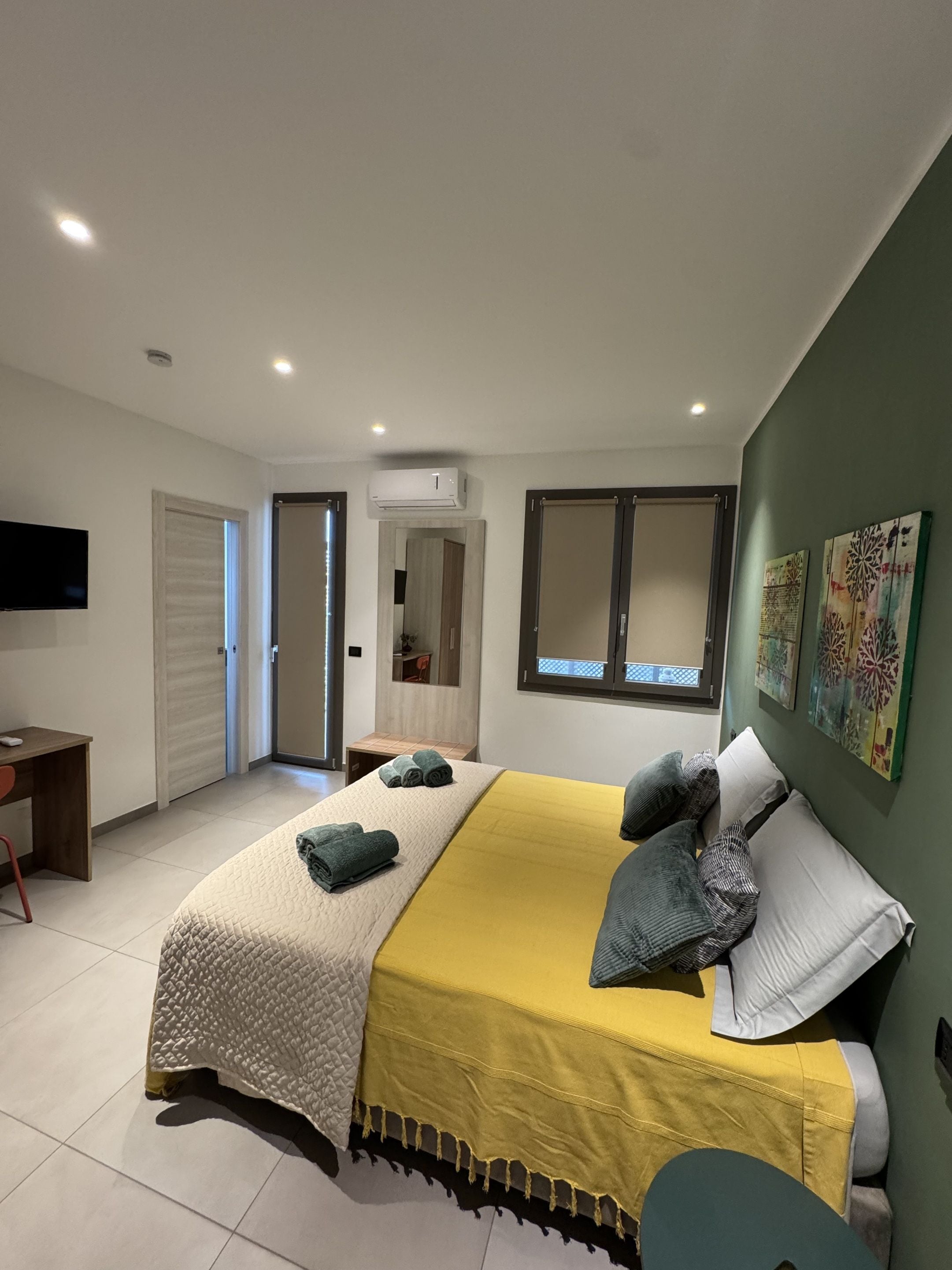 Un dormitorio moderno con cama, mesitas de noche, escritorio y televisor.