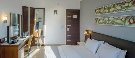 A modern hotel room with a large bed, a desk with a flat-screen TV, a chair, and a wardrobe.