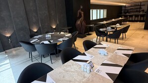 A modern dining area with a long table, black chairs, and a central sculpture. - Avenue Suites (Lagos)