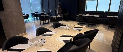 A modern conference room with a large table, black chairs, and a statue.