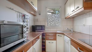 Een kleine keuken met een ingebouwde oven, magnetron en vaatwasser.