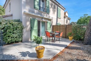 A two-story building with a patio area featuring a table and chairs, a small tree, and a yellow pot. - House 60m², 500m from the beach for 4 (Saint-Brevin-les-Pins)