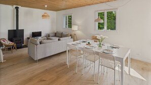 A modern living room with a sofa, a dining table with chairs, a fireplace, and large windows. - House for 6 with garden, 900 m from the beach (Penmarch)