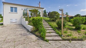 Un edificio bianco con tetto in tegole, una piccola finestra e un camino. Un vialetto sterrato conduce all'ingresso.