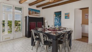 Zona pranzo con soffitto in legno, un grande tavolo imbandito per sei persone e vista panoramica attraverso porte in vetro.
