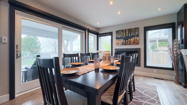 A dining area with a large table, chairs, and a fireplace.