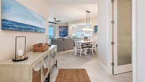 A modern kitchen with white cabinets, a dining area with white chairs, and a large painting on the wall. - Experience the Ultimate Vacation at Regatta! (Naples)