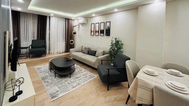 A modern living room with a sofa, coffee table, and dining table set. - Two-Bedroom Apartment in Taksim - No: 3 (İstanbul)