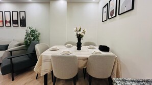 A dining area with a table set for four, surrounded by chairs, a vase of flowers, and framed artwork on the walls. - Two-Bedroom Apartment in Taksim - No: 3 (İstanbul)