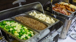 A buffet with various food options including broccoli, cauliflower, and bacon.