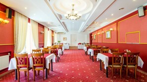 Ein Bankettsaal mit Tischen und Stühlen, einem roten Teppich und einer Kristallleuchter.